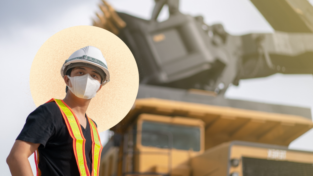 A reclamation worker in a hard hat stands in front of blurred construction equipment.