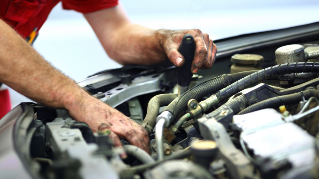A mechanic investigates under the hood of a car.