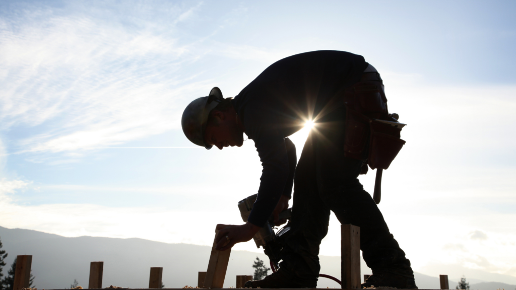 The sun peeks behind a construction worker.