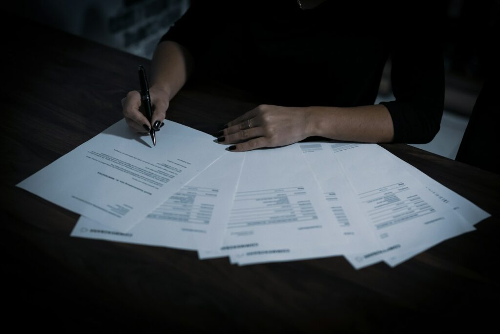 A darkly lit photo of a person reviewing contract documents.