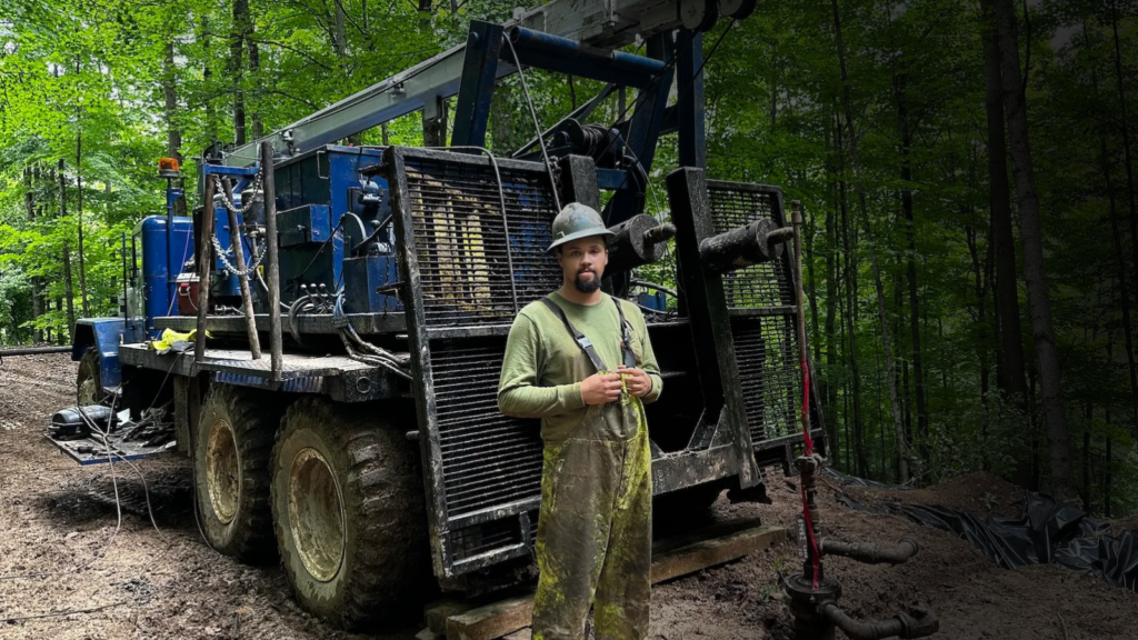 A worker stands in front of a plugged orphaned well.